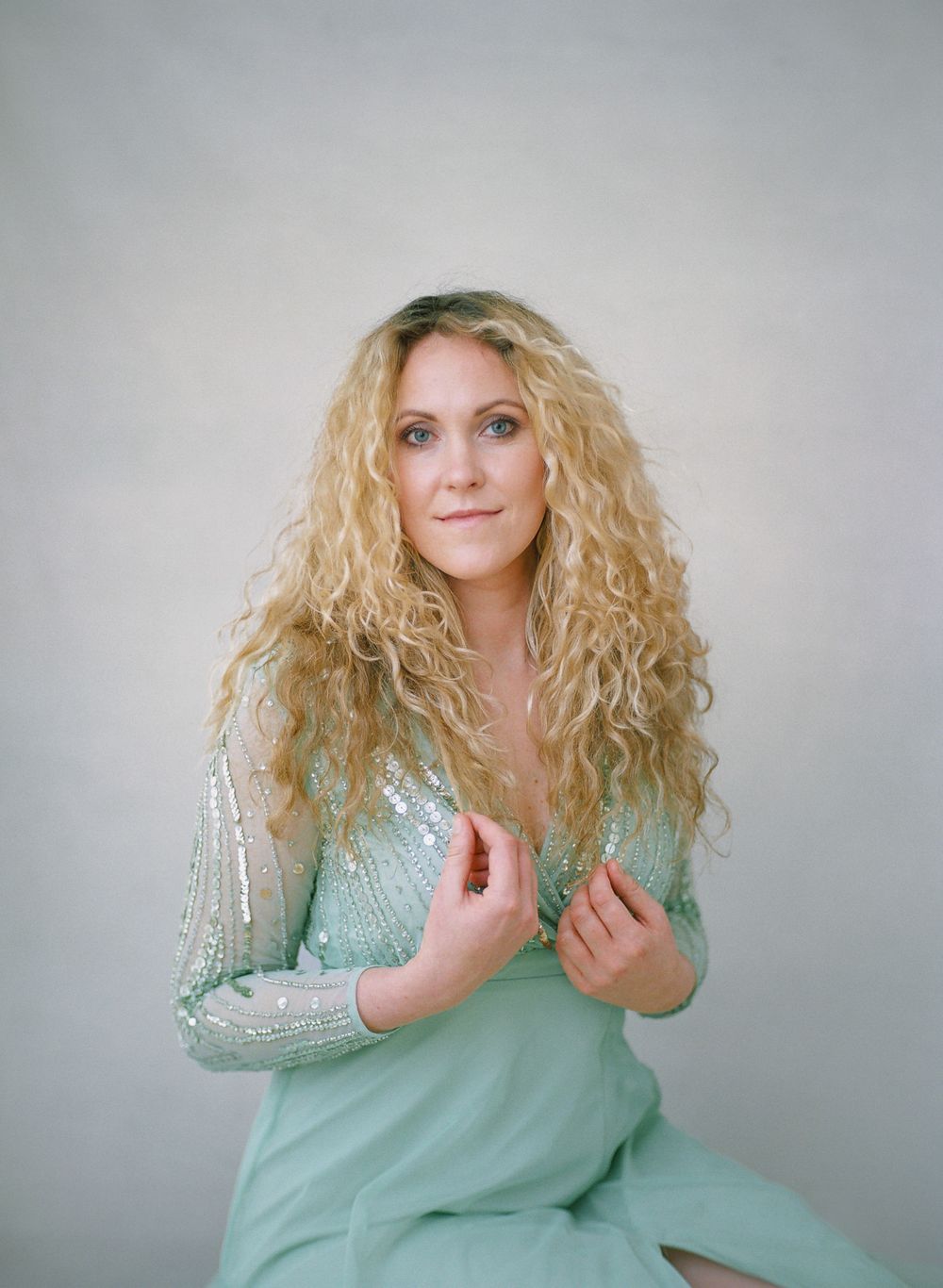 Portrait in mint sequined dress against light gray background.