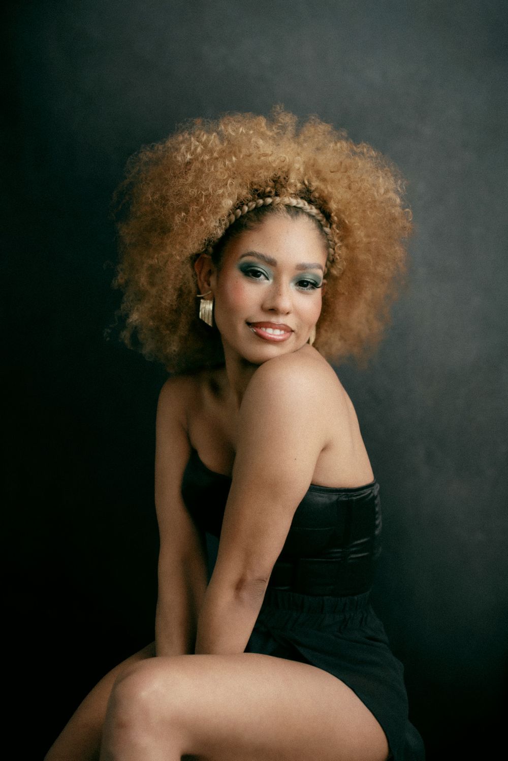 Glamorous portrait featuring afro hairstyle, sparkly headpiece and black dress.