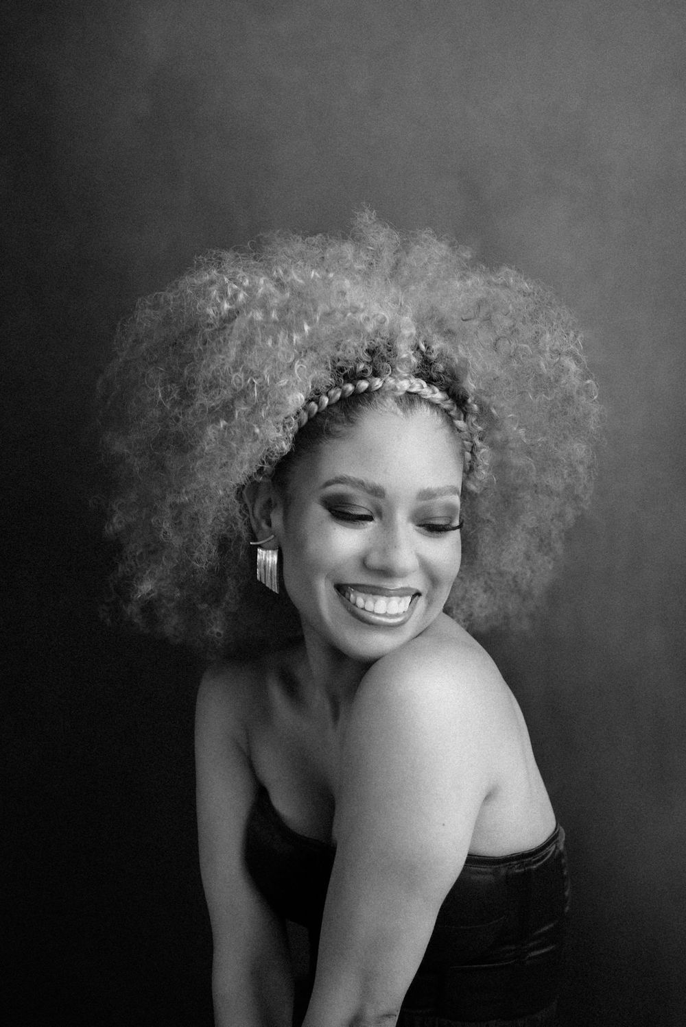 Joyful black and white portrait with natural afro hair and elegant styling.