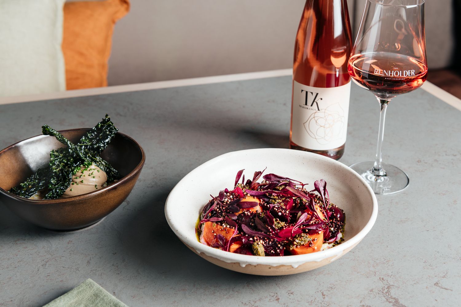 A series of elegant plated dishes and TK wine arranged on a gray stone table at The Runholder by August and Vine