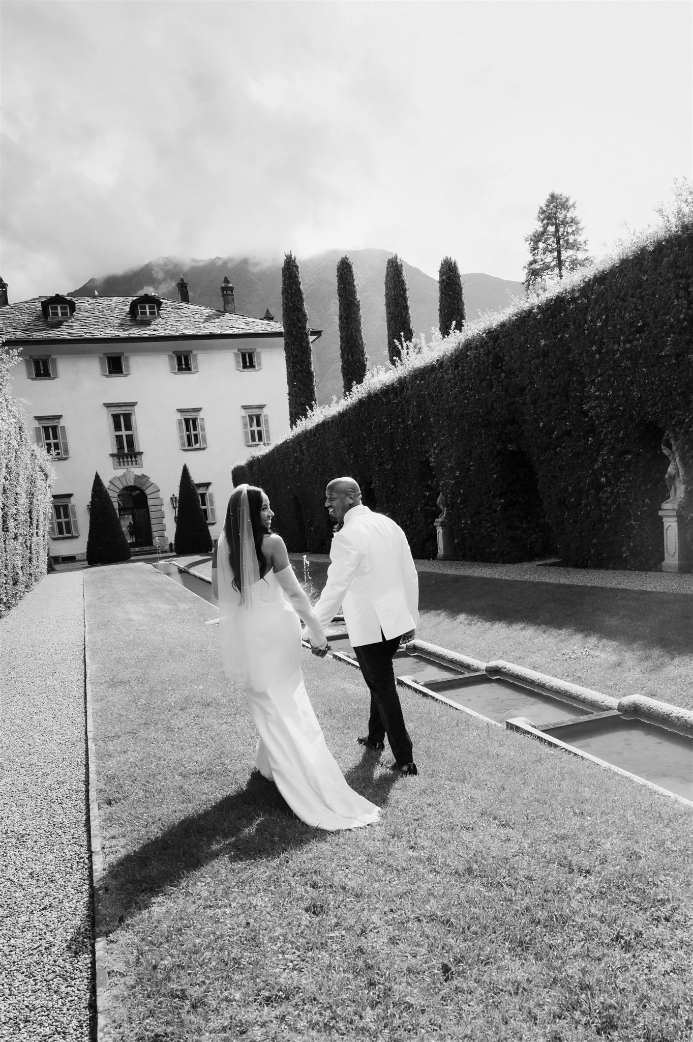 Black and white photos of a couple dancing and twirling on a grassy lawn near a villa.