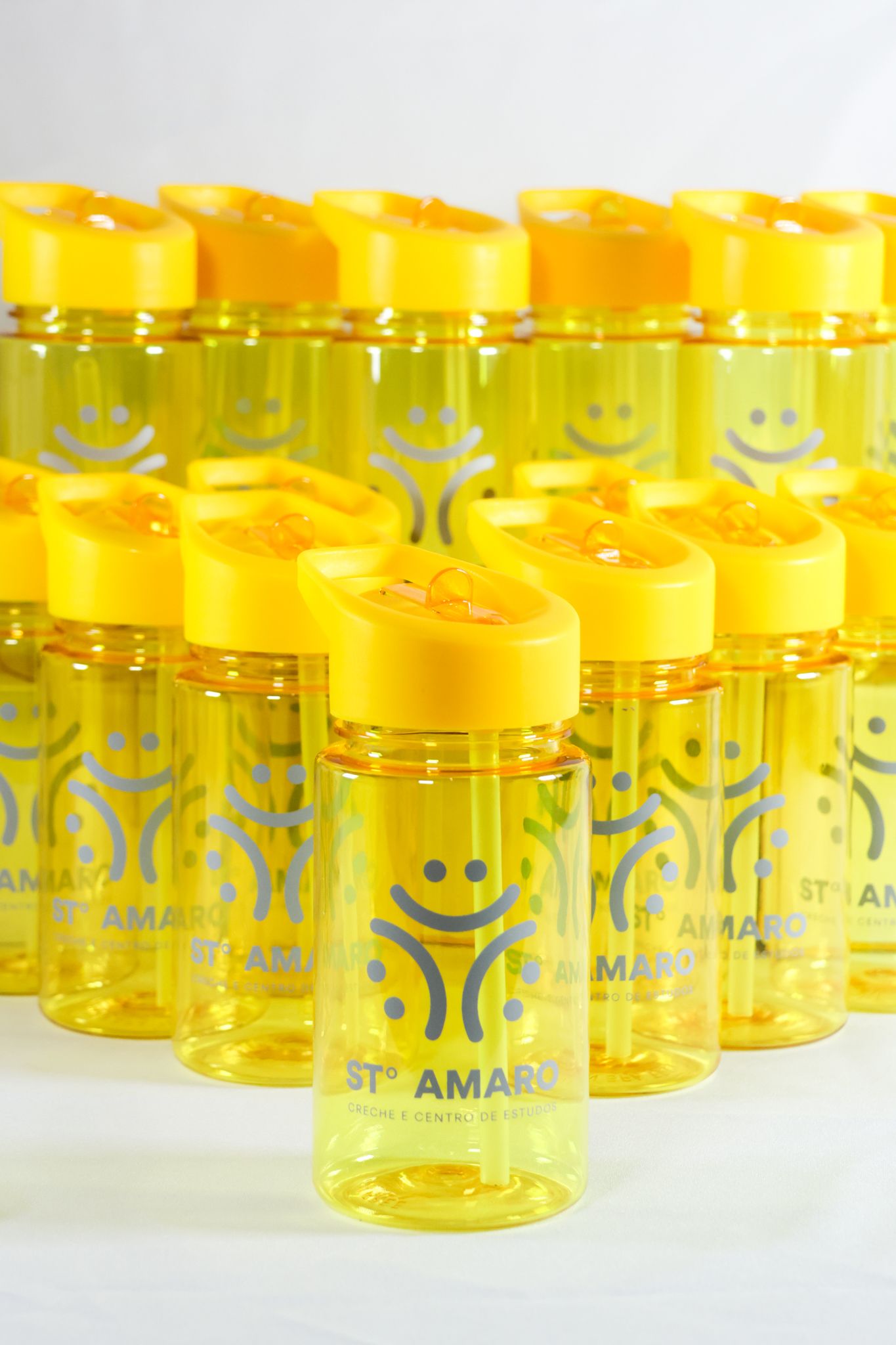 Yellow plastic jars with smiley face designs arranged in rows on a white surface.