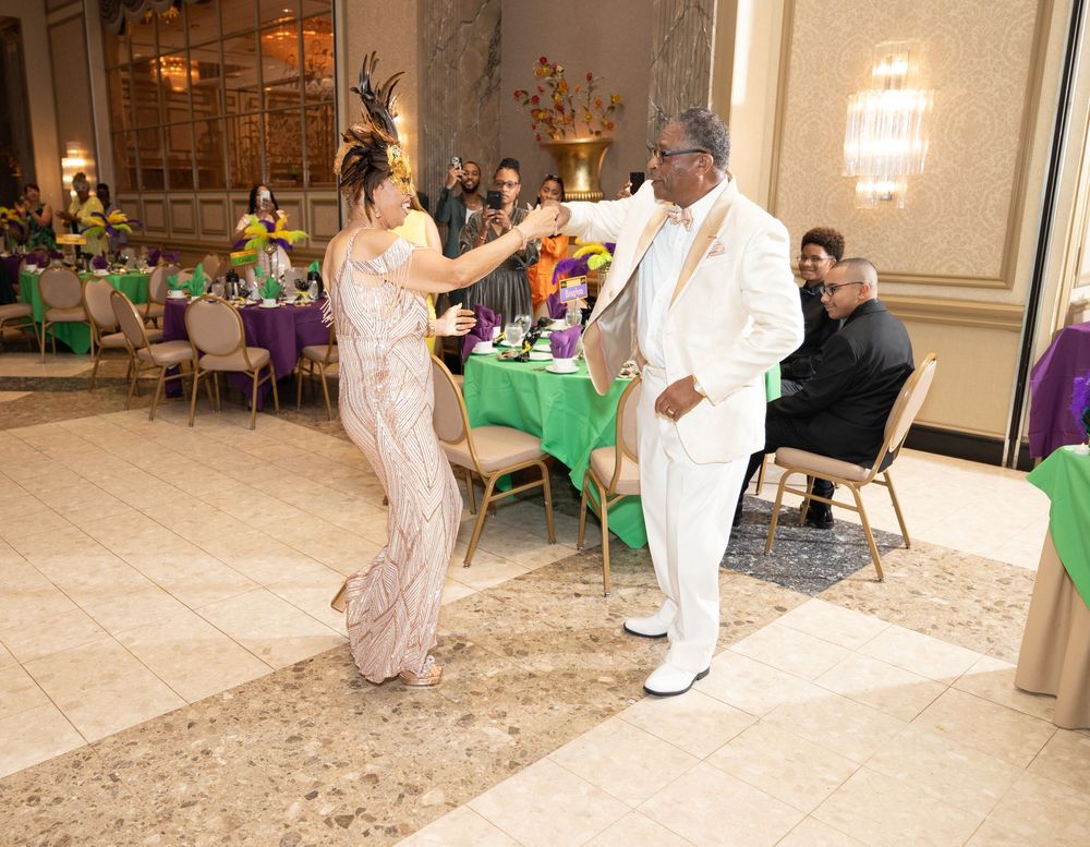 Guests dancing and celebrating at an elegant event decorated in purple and green.