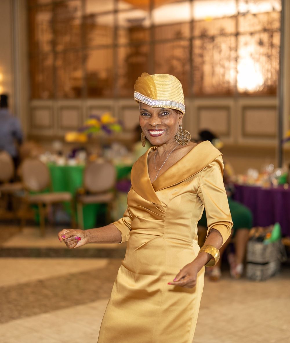 Person in gold dress dancing at an indoor celebration venue.