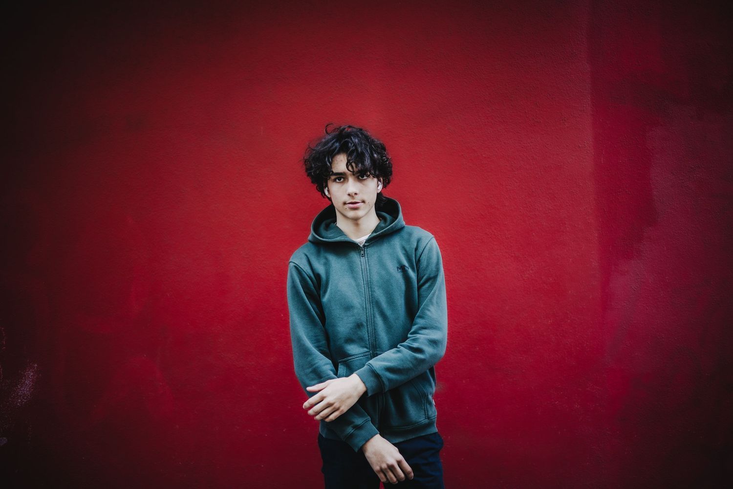 Artistic portrait series against a deep red background showing someone in a blue zip-up hoodie.