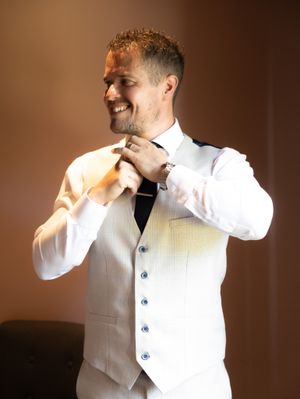 A person wearing a white dress shirt and vest poses expressively in a series of connected profile shots against a dark background.