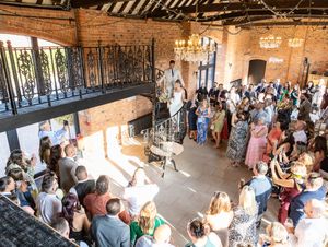 Wedding guests mingle and socialize in a rustic brick venue with string lights creating a warm ambiance.