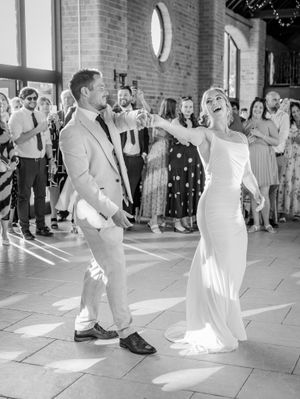 A wedding couple performs a choreographed first dance sequence showing various fun dance moves at their reception.