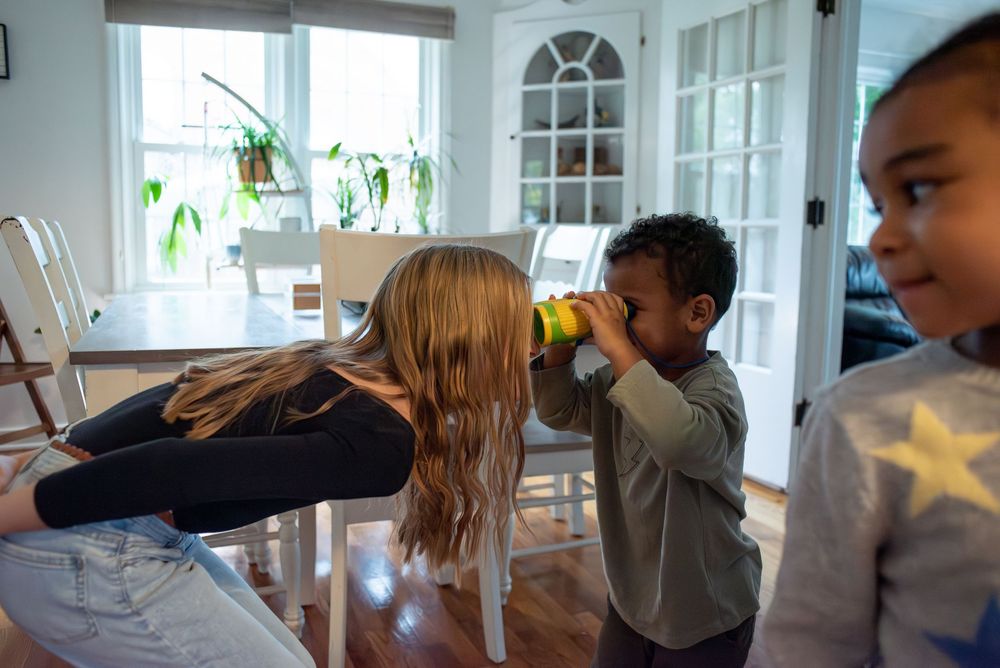 Siblings playing together with binoculars and smiling in their family home in Lansing, Michigan
