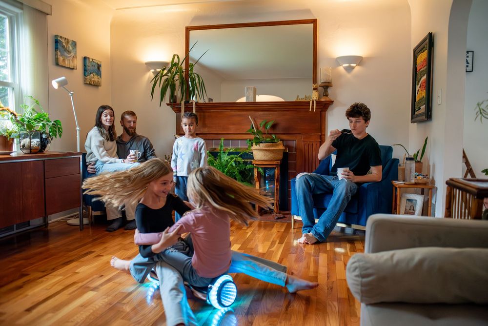 Parents sitting and watching their kids play and spin in their home living room in Lansing, Michigan