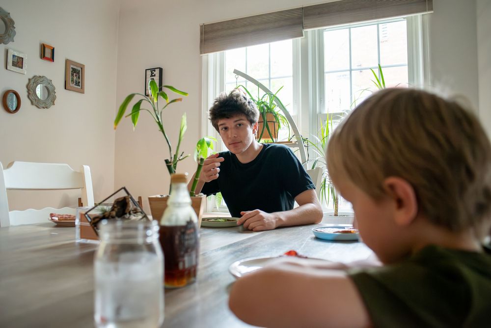 A older and younger brother eating brunch together at the family dining room table at home in Lansing, Michigan
