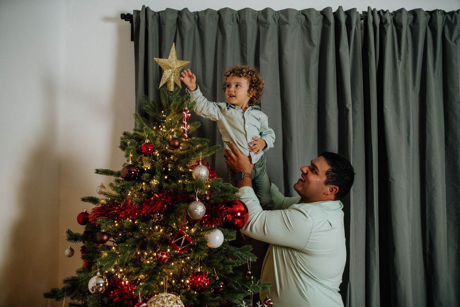 A sequence of four photos showing someone placing a star decoration on top of a decorated Christmas tree.