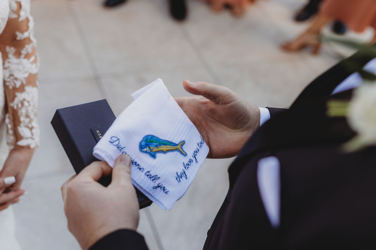 Hands holding small cards with blue drawings at an outdoor event.