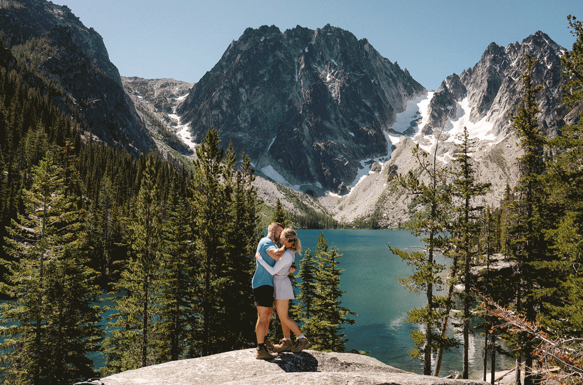 A stunning view of snow-capped mountain peaks and evergreen forest along a hiking trail in the Enchantments, Colchuck Lake proposal