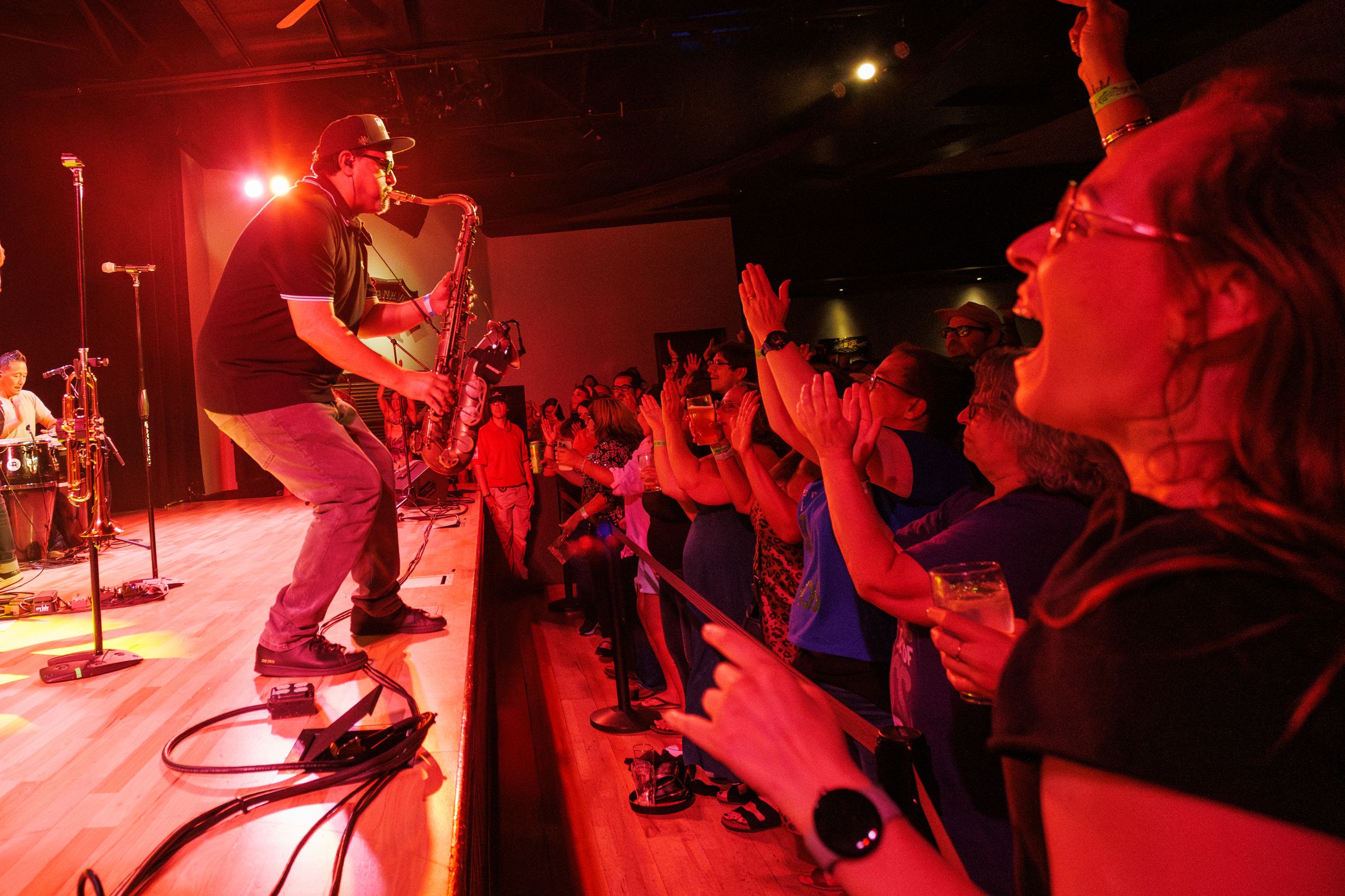 Musicians perform on stage bathed in dramatic red lighting during a live concert performance.