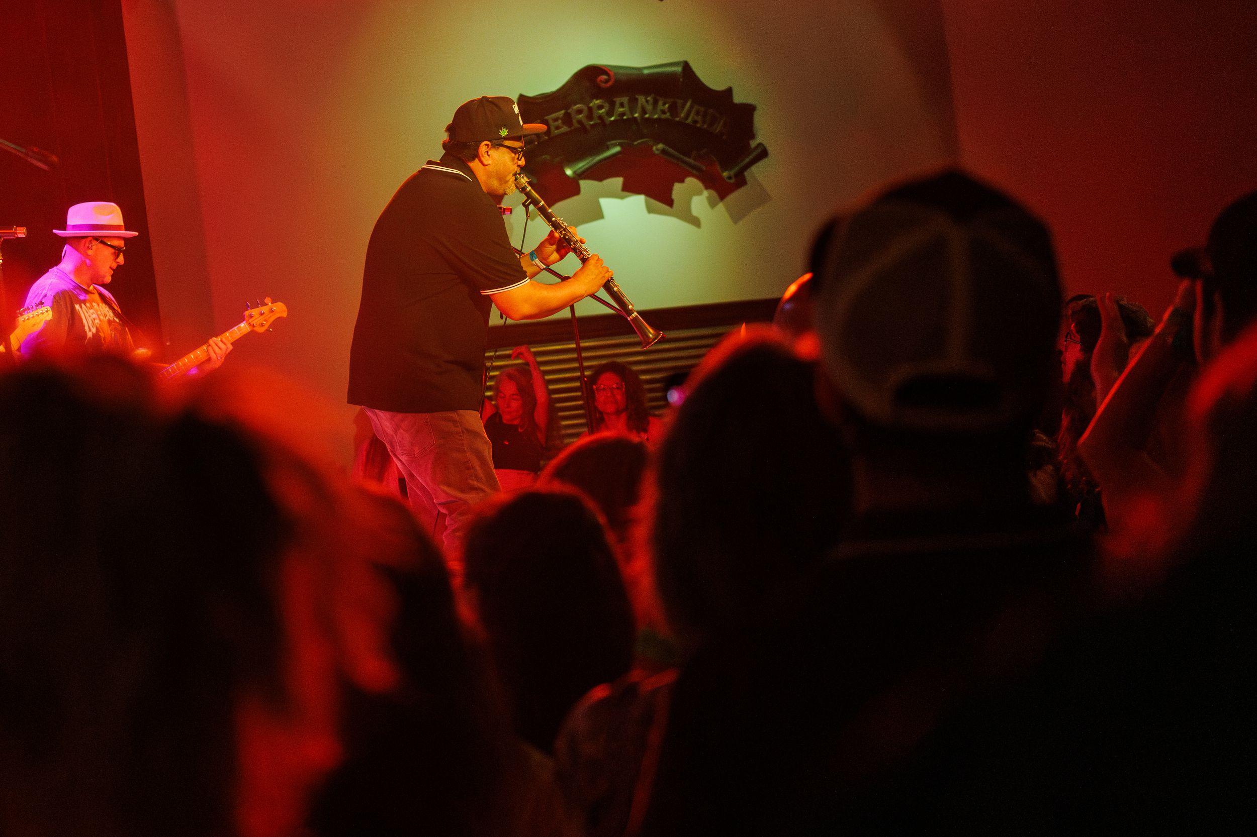 Musicians perform on stage in dramatic red lighting during a concert performance.
