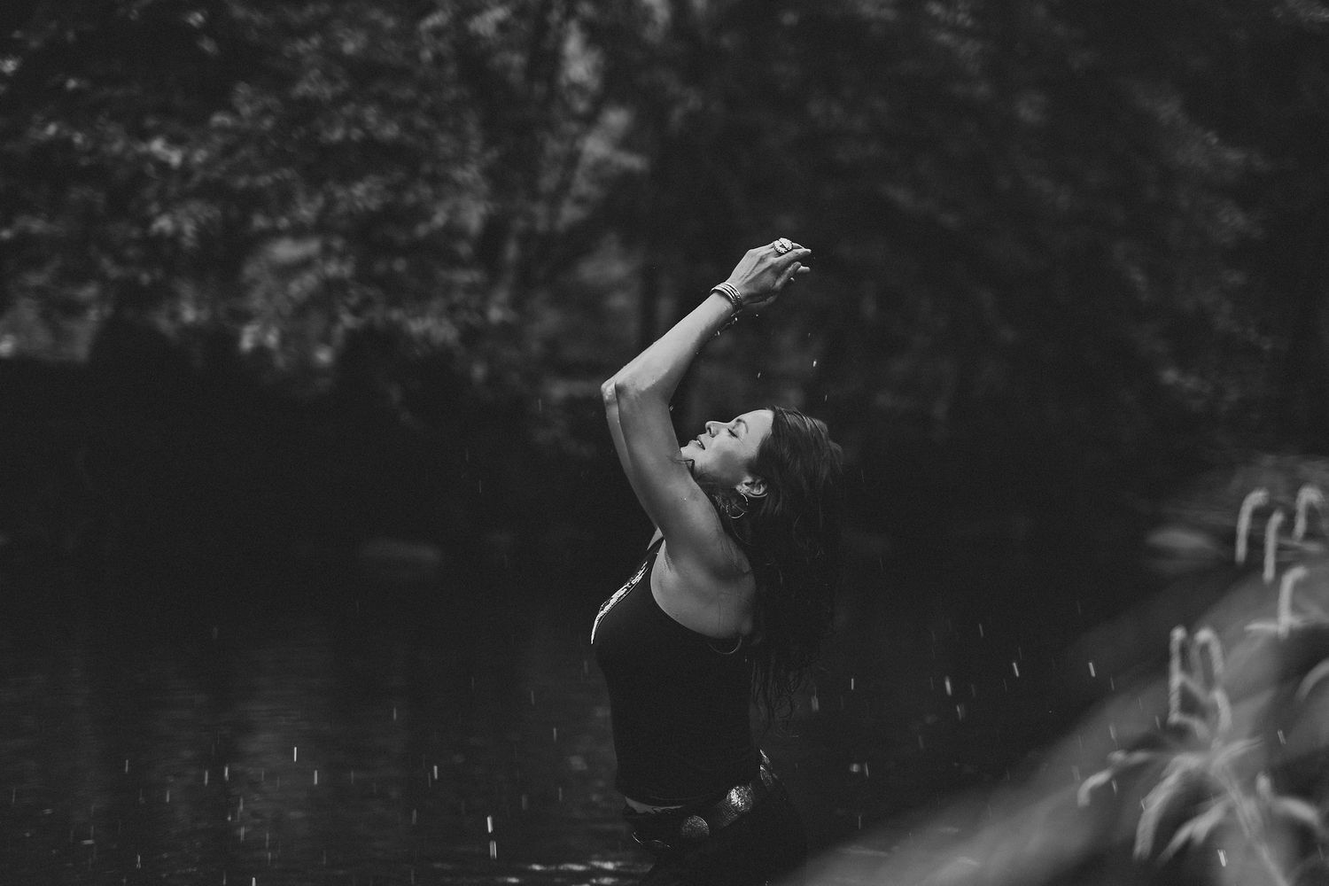 A black and white photograph shows a frog splashing into rippling water creating circular patterns on the surface.