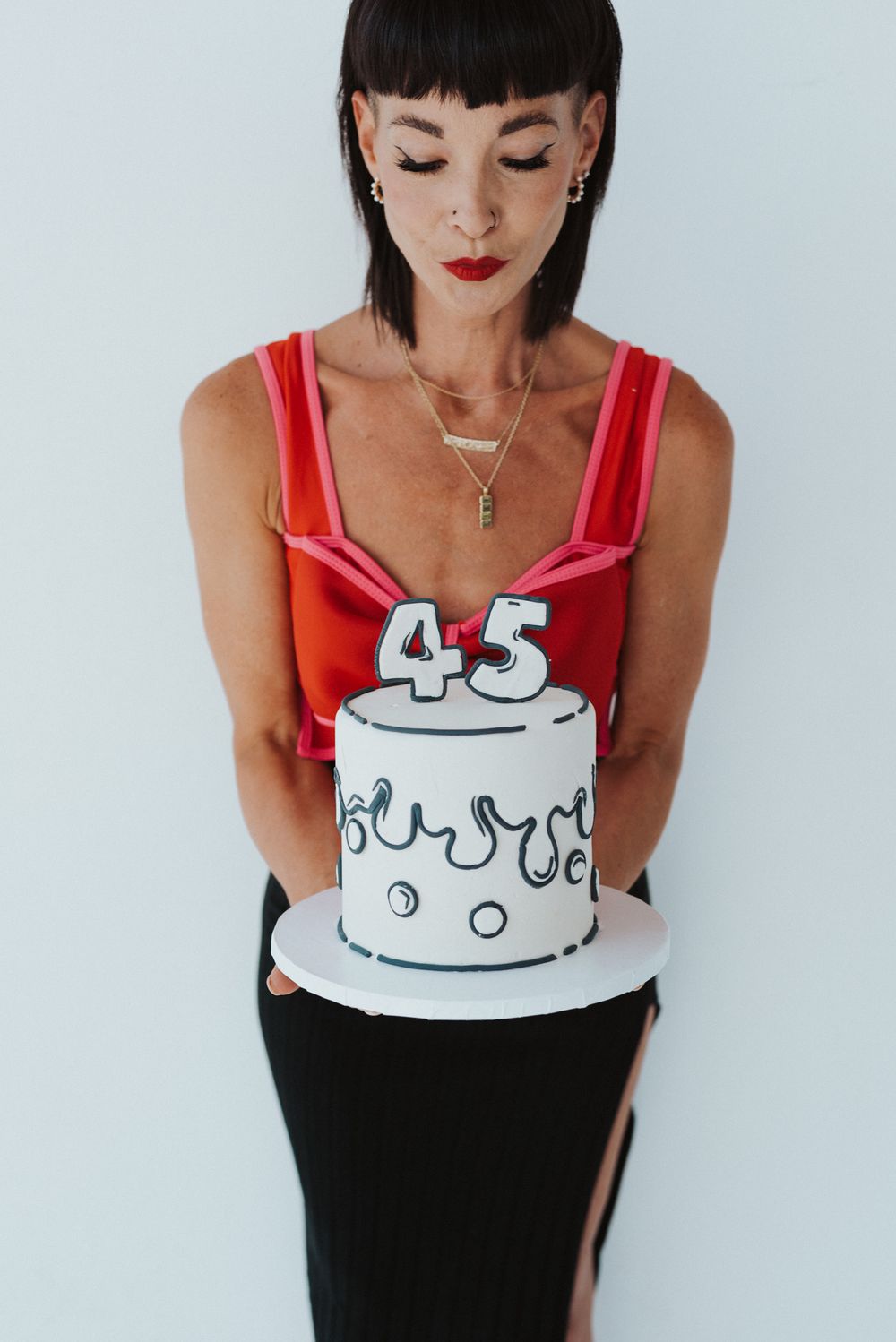 Red top with illustrated birthday cake design in minimalist studio setting.