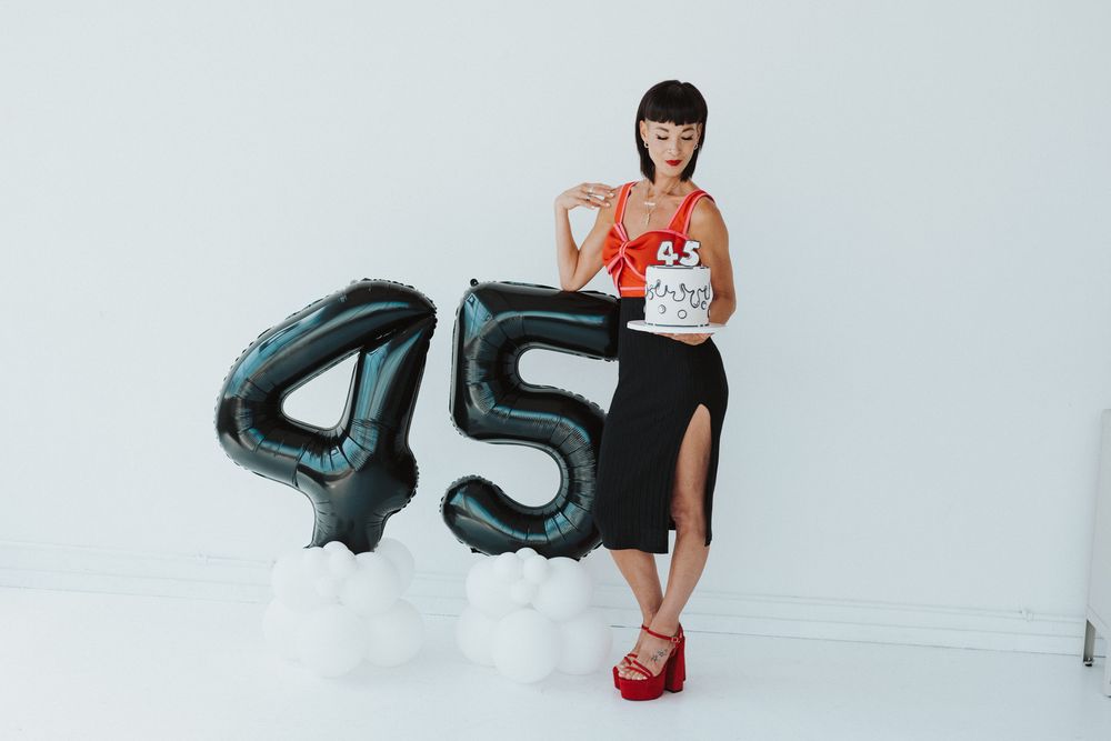 Black balloon numbers against white studio backdrop in fashion shoot.