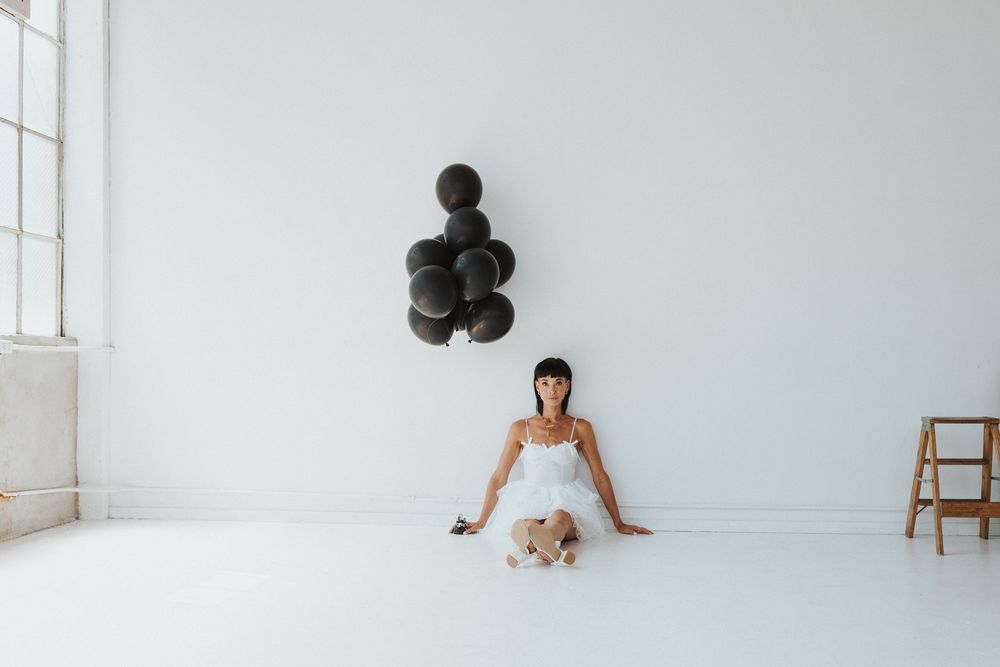 Elegant white dress and heels against minimalist white background in fashion photoshoot.