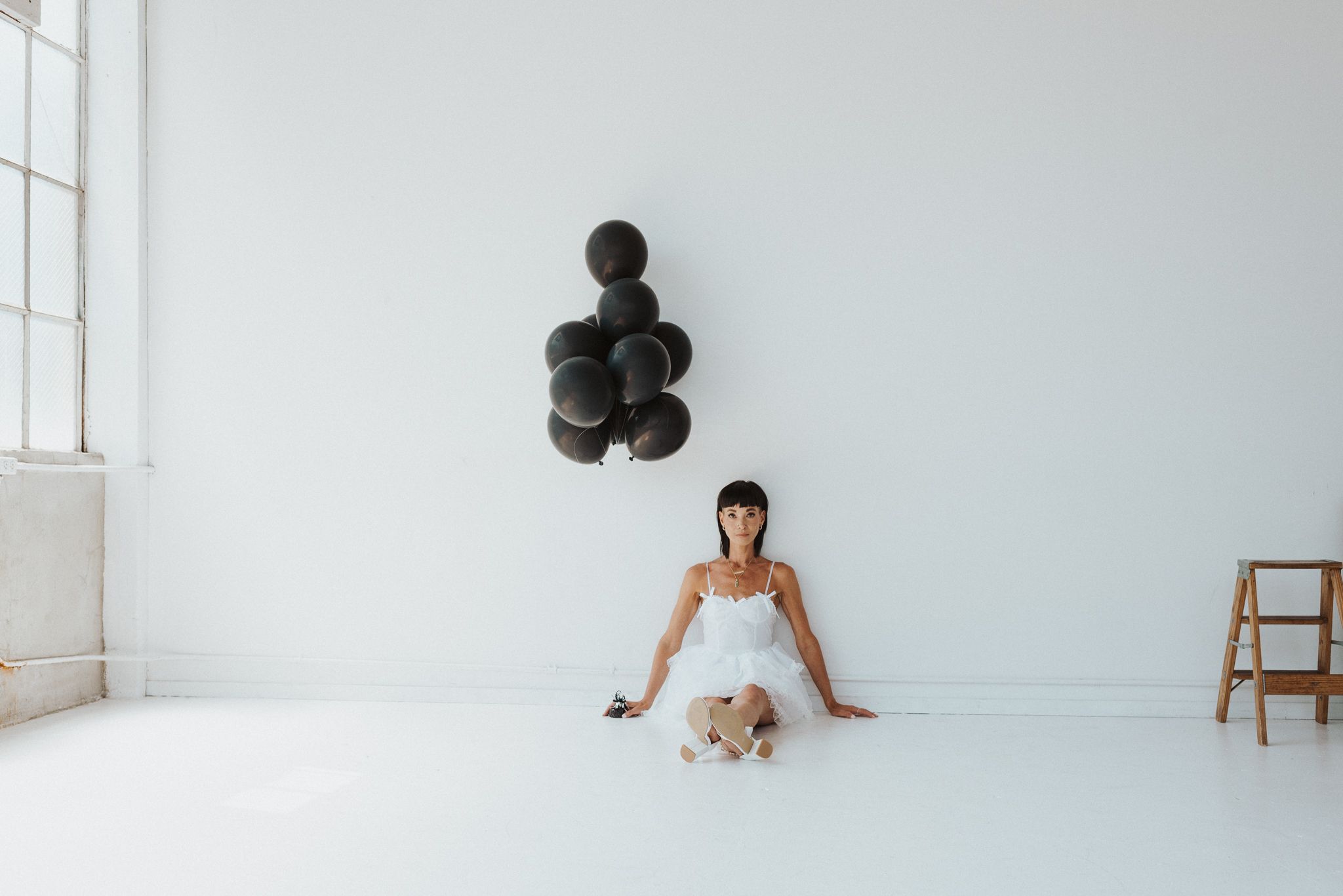 Elegant white dress and heels against minimalist white background in fashion photoshoot.