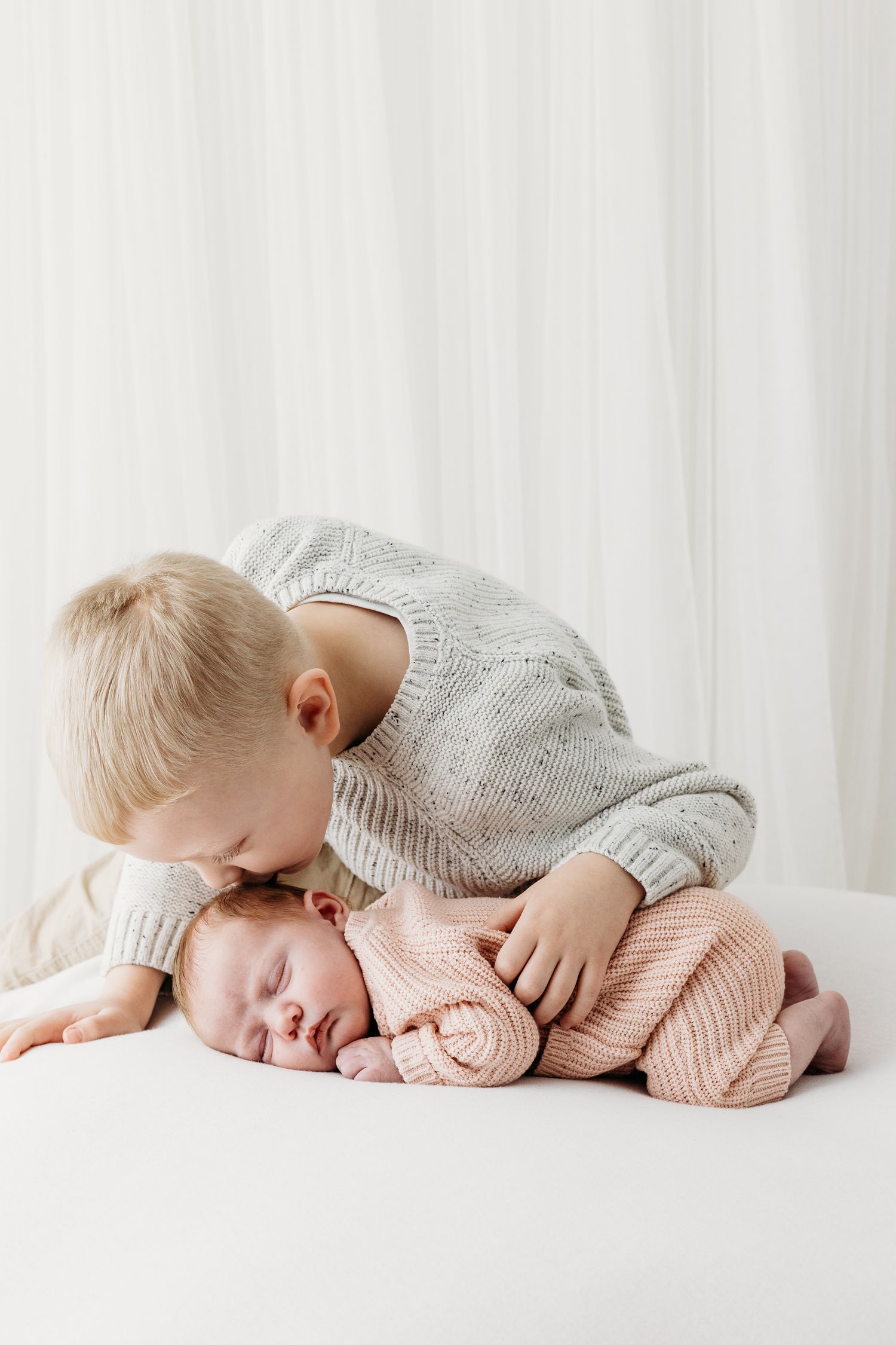 Nottingham newborn photographer capturing tender sibling moments in Mapperley studio with soft natural light and neutral tones.