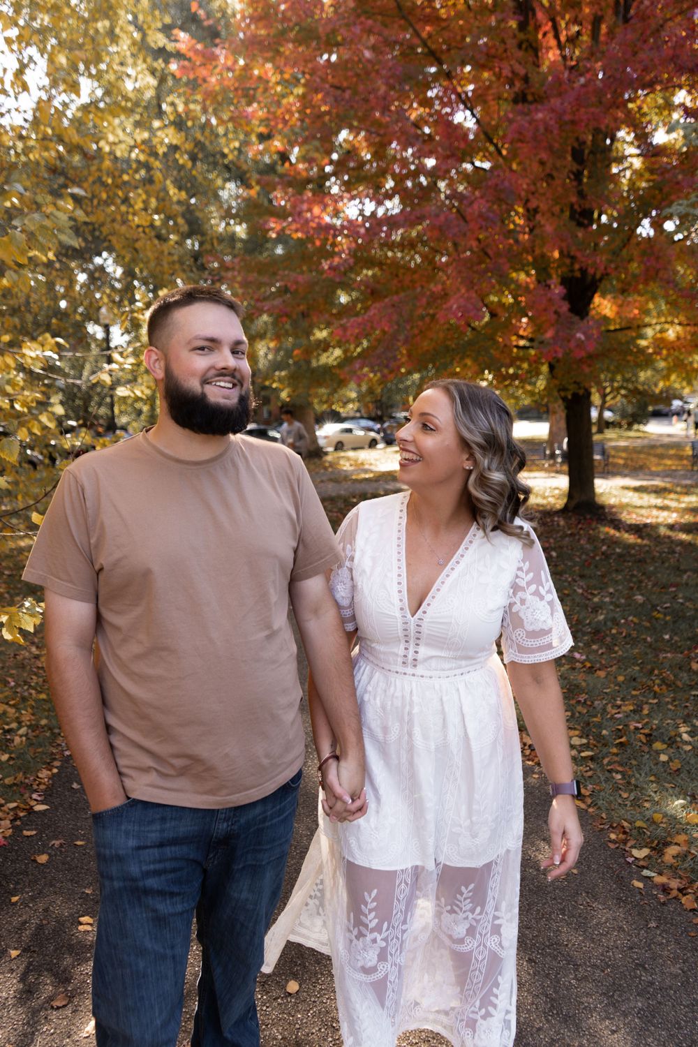Beautiful couple share loving moments in a fall outdoor setting with vibrant autumn foliage in the background.