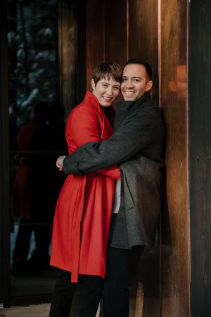 Intimate moments captured against a dark wooden cabin wall in winter.