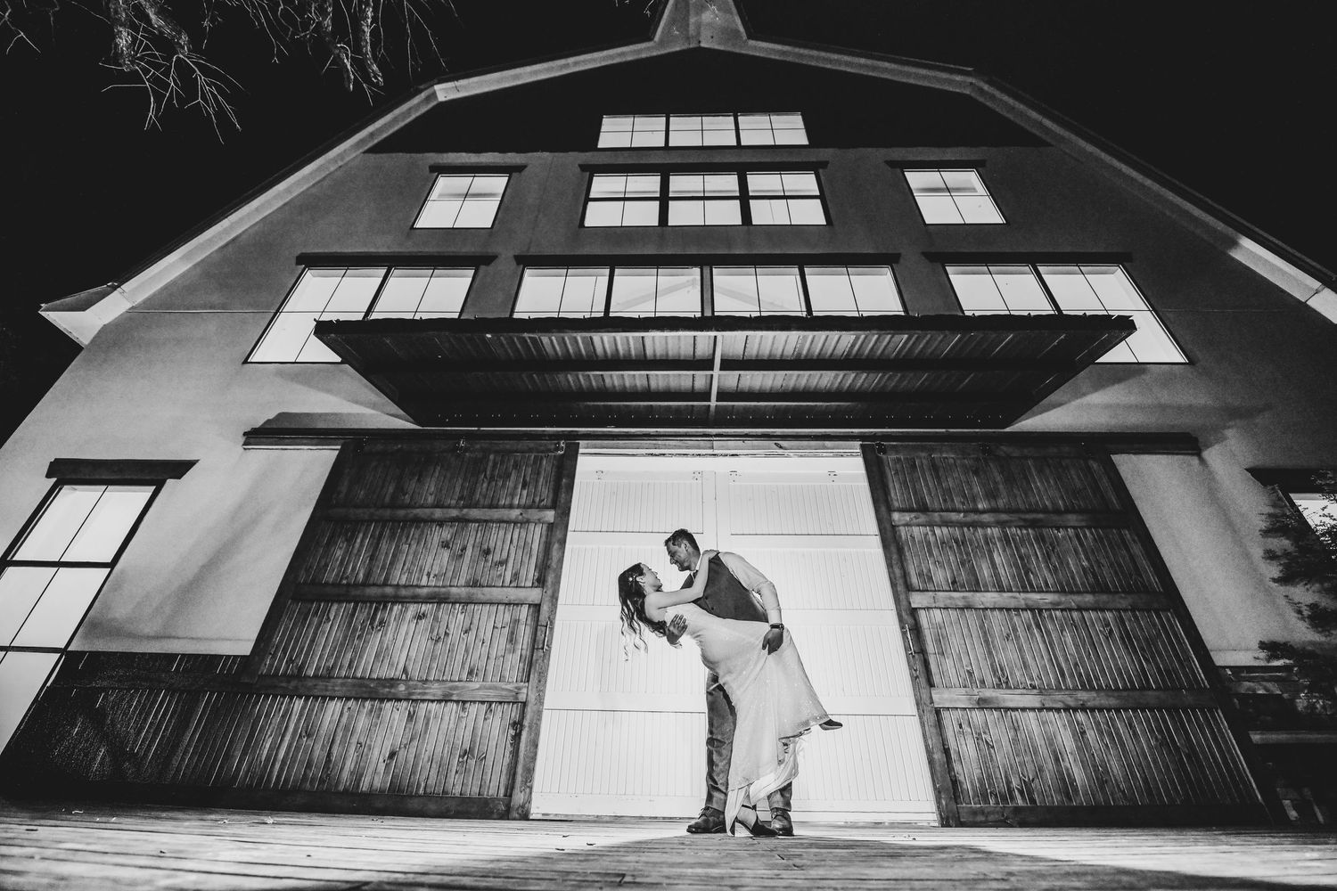 romantic black and white dramatic photo of groom dipping his bride on the steps of oak and ivy wedding venue