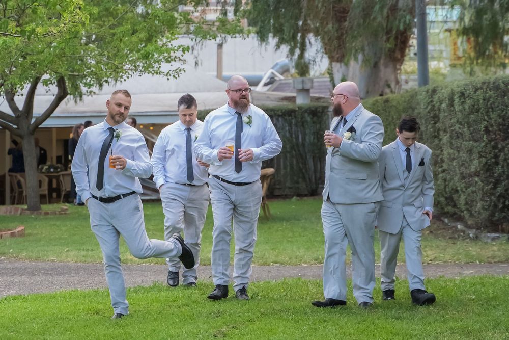 A sequence of shots showing a lighthearted moment in light blue suits during an outdoor wedding shoot.
