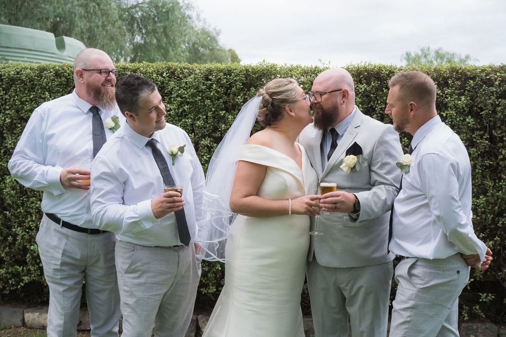 Group in formal wedding attire sharing a special toast moment during outdoor celebration at garden venue.