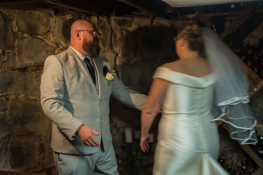 A couple dances together in a rustic barn setting during a wedding celebration.