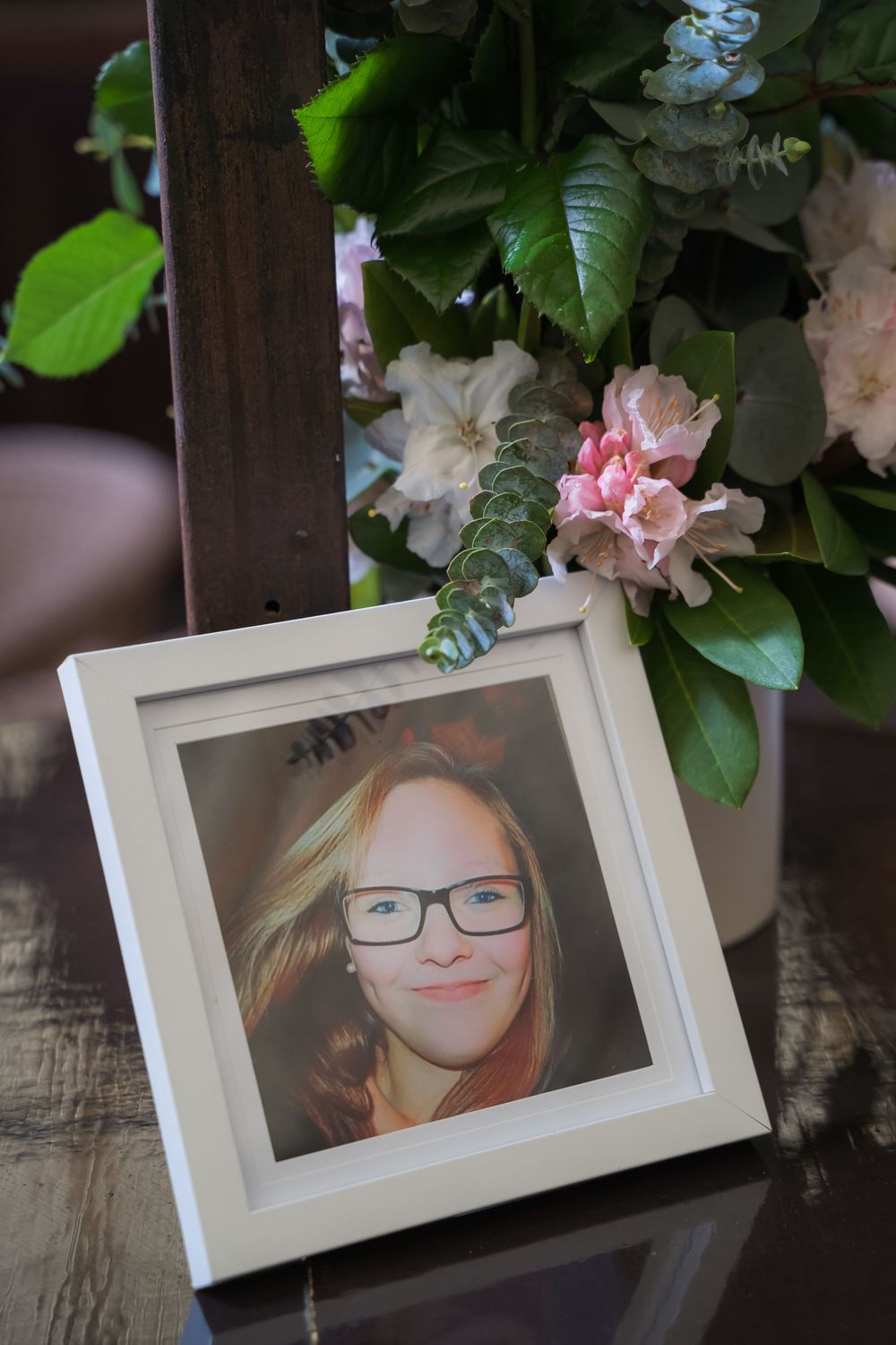Three white framed photographs displayed against a dark wooden surface with green and white floral decorations.