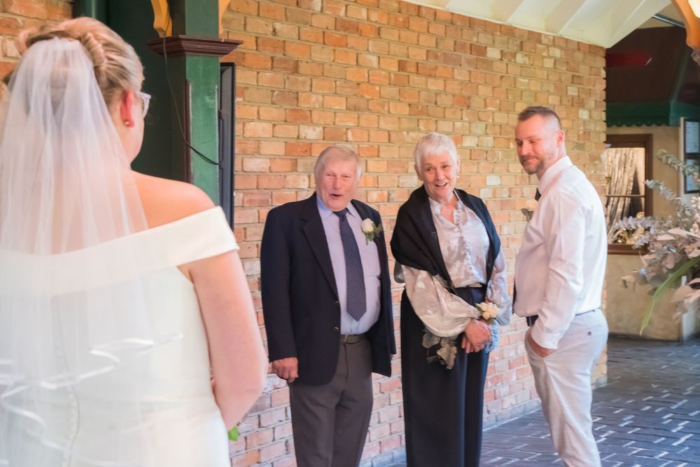 A wedding ceremony takes place inside a rustic brick-walled venue with people gathered for the intimate service.