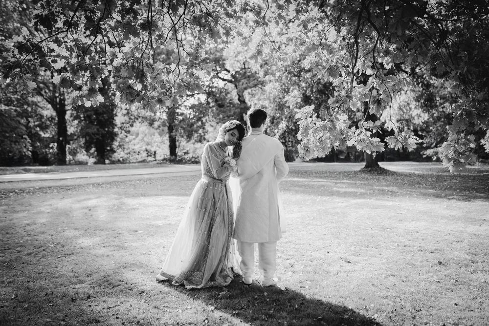 A romantic black and white sequence of a couple walking through a sunlit garden setting during a wedding celebration.