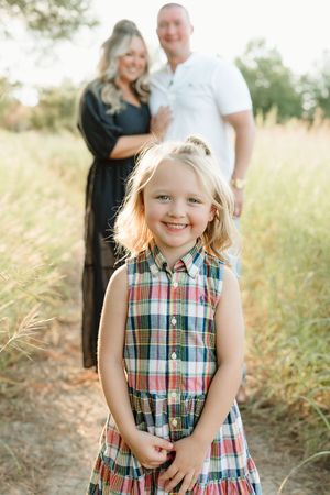 Joyful outdoor family photo session in golden grass field at sunset.