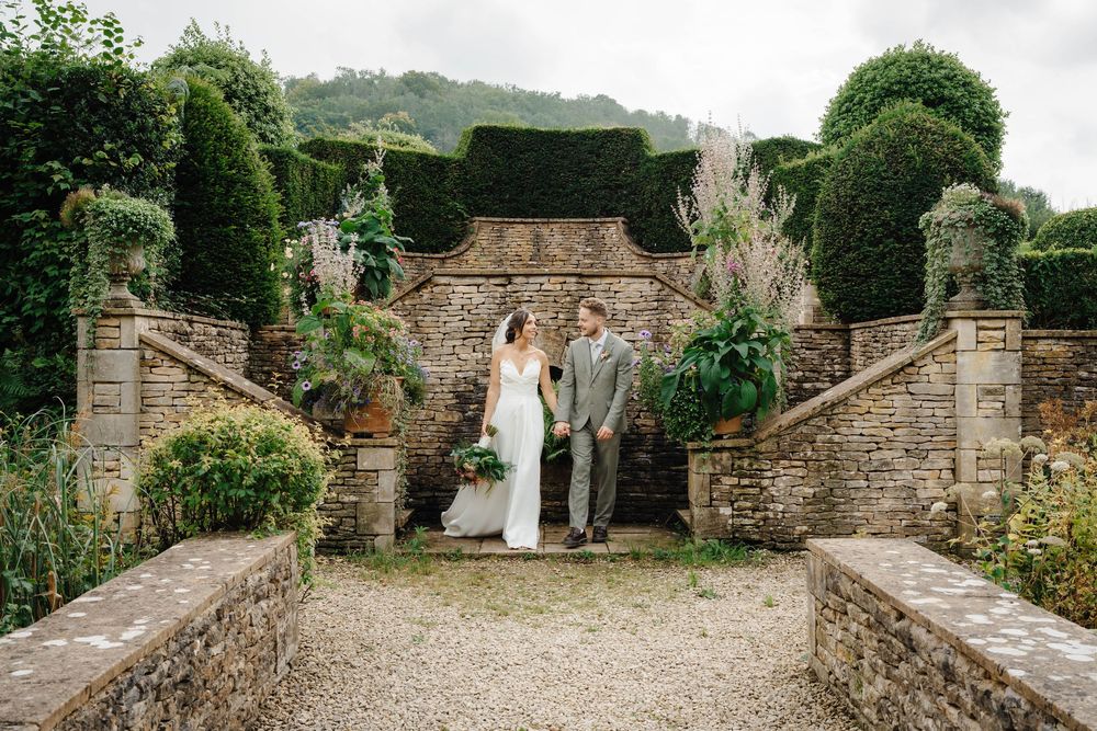 Owlpen Manor wedding photographer Zara Davis Photography Cotswolds Gloucestershire bride and groom walking along steps bridge