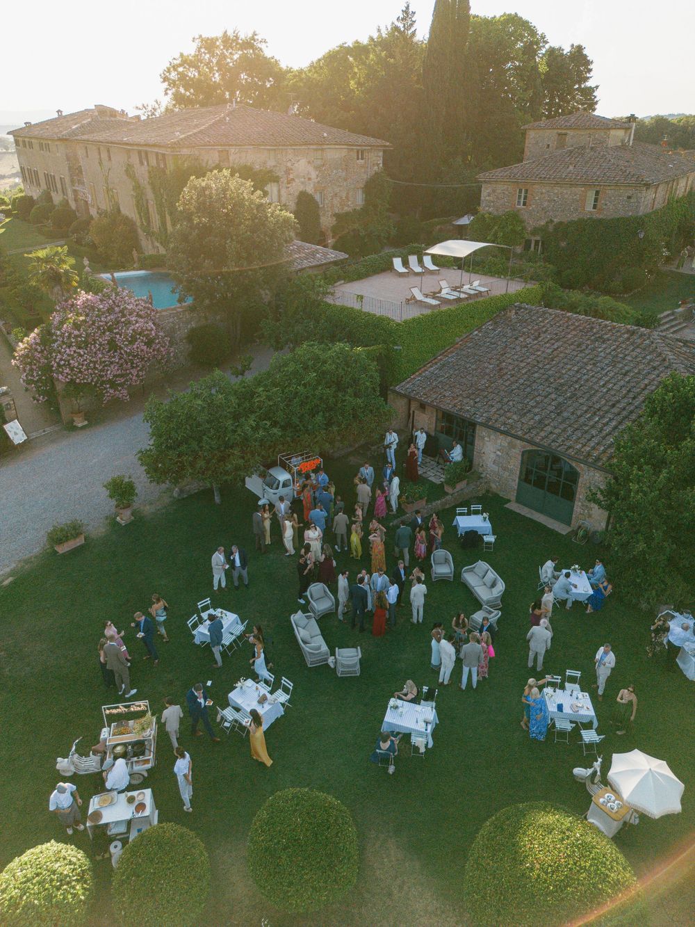 Elegant outdoor garden reception setup with tables and chairs arranged on a lawn at dusk at Borgo Stomennano.