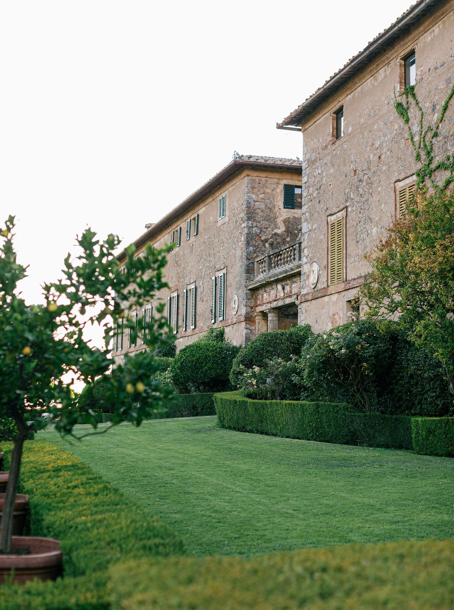 Stylish Borgo Stomennano sit along a green grassy hillside surrounded by manicured landscaping.