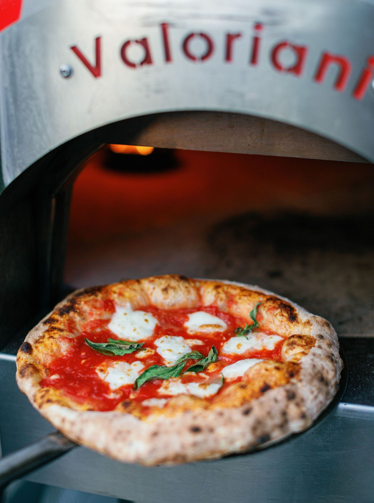 Traditional Neapolitan pizza with fresh mozzarella and basil cooking in a wood-fired oven shown in sequential stages.