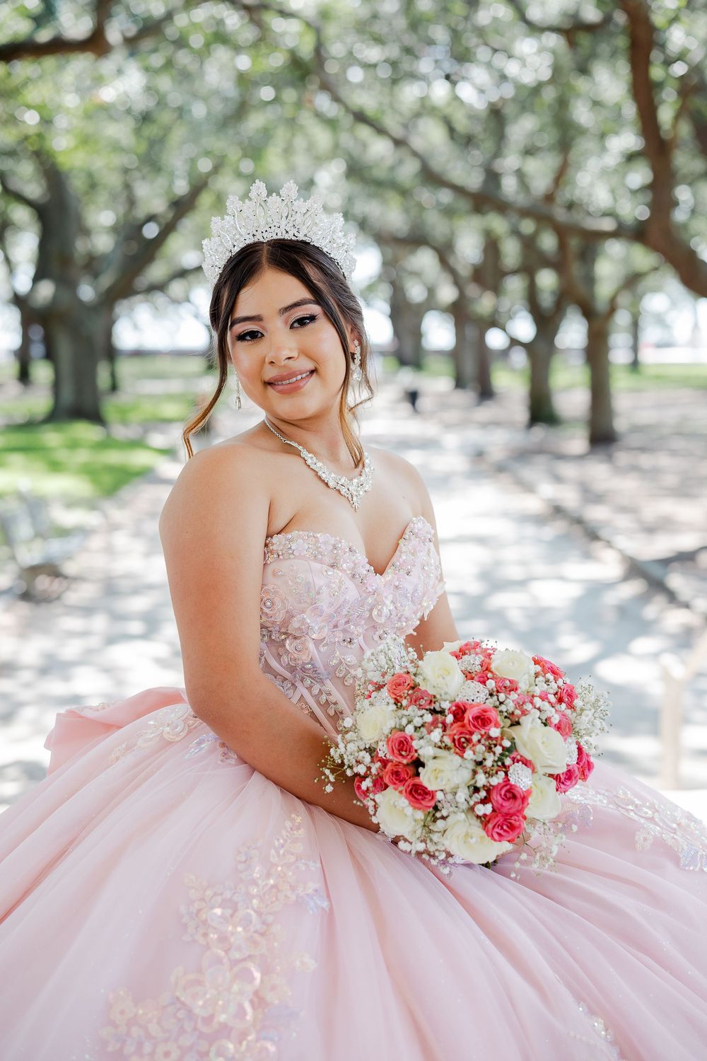 Series of dreamy outdoor bridal photos featuring a soft pink ballgown dress and red and white floral bouquet under blooming trees.