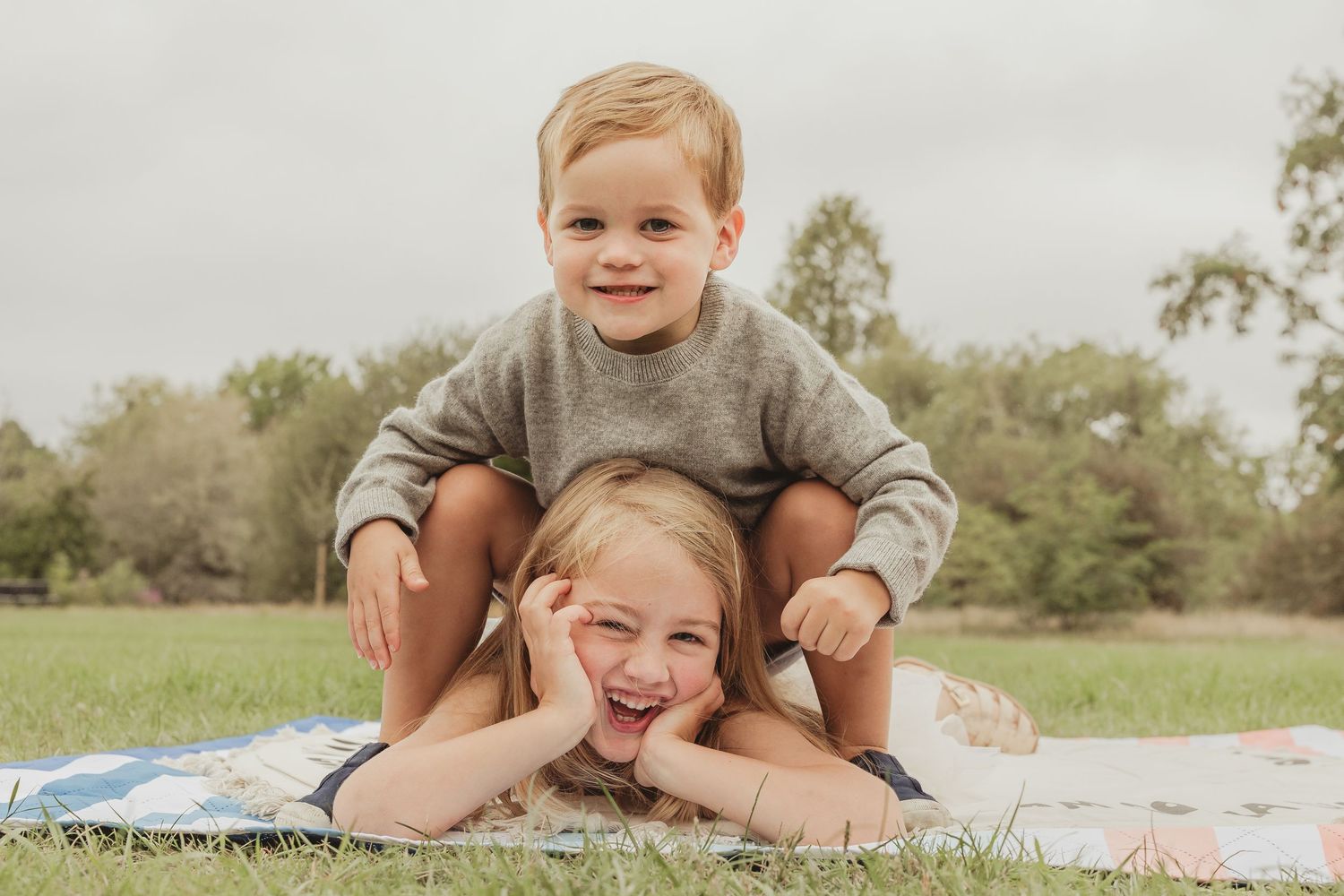 Family enjoying playful moments together on picnic blanket outdoors.