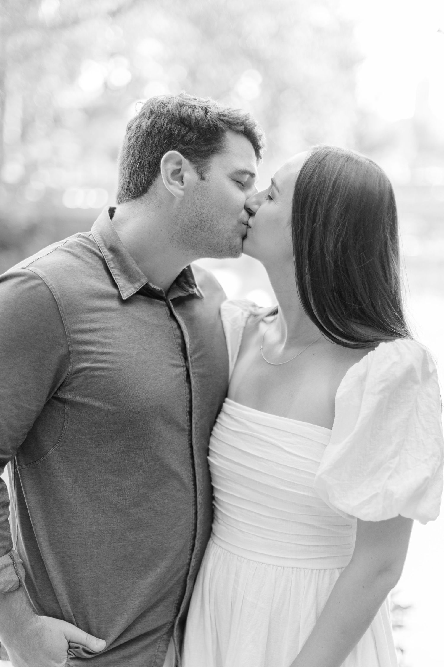 A romantic black and white sequence of a couple in a polo shirt and white dress sharing tender kisses outdoors.