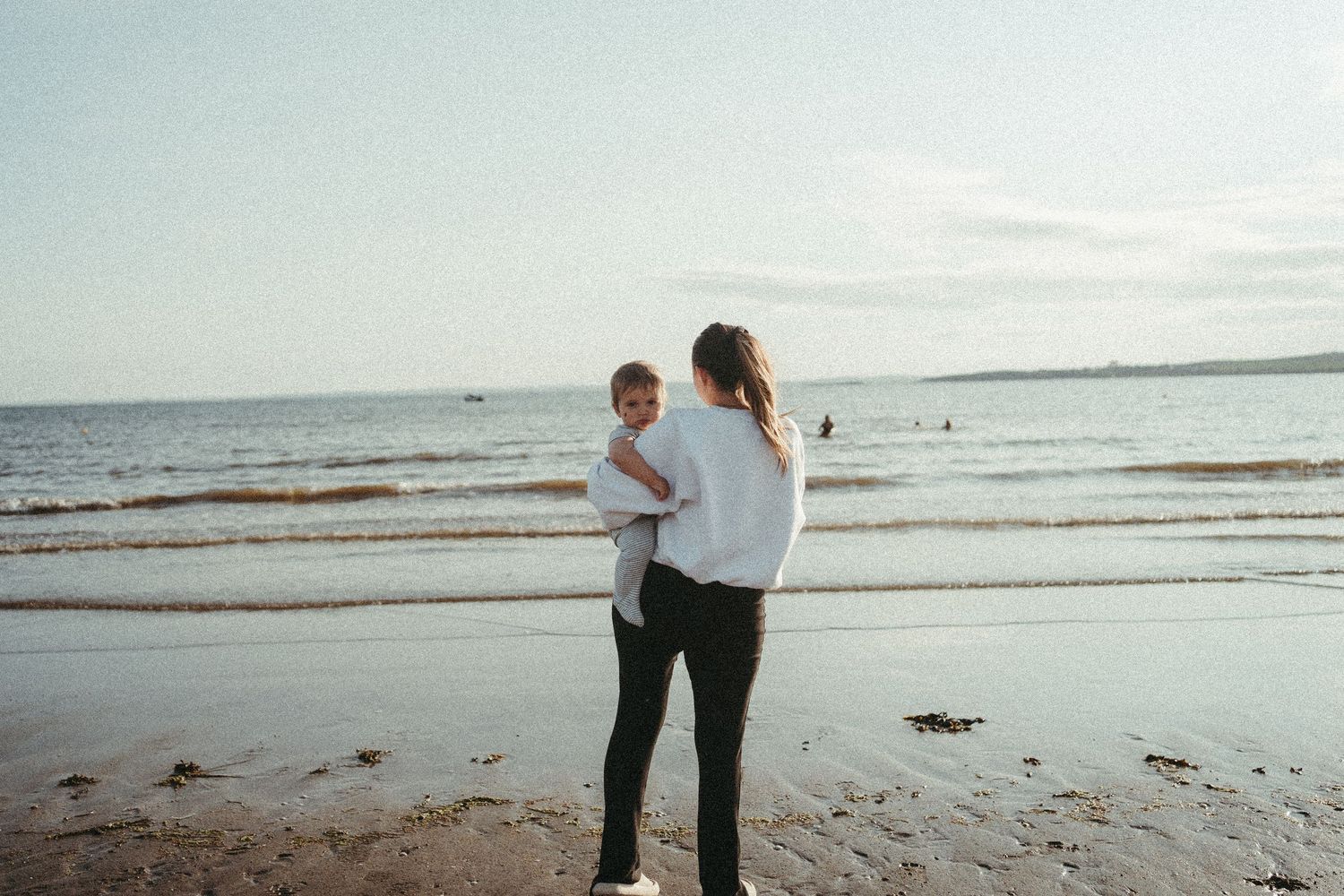Couple walking together along peaceful beach shoreline at sunset.