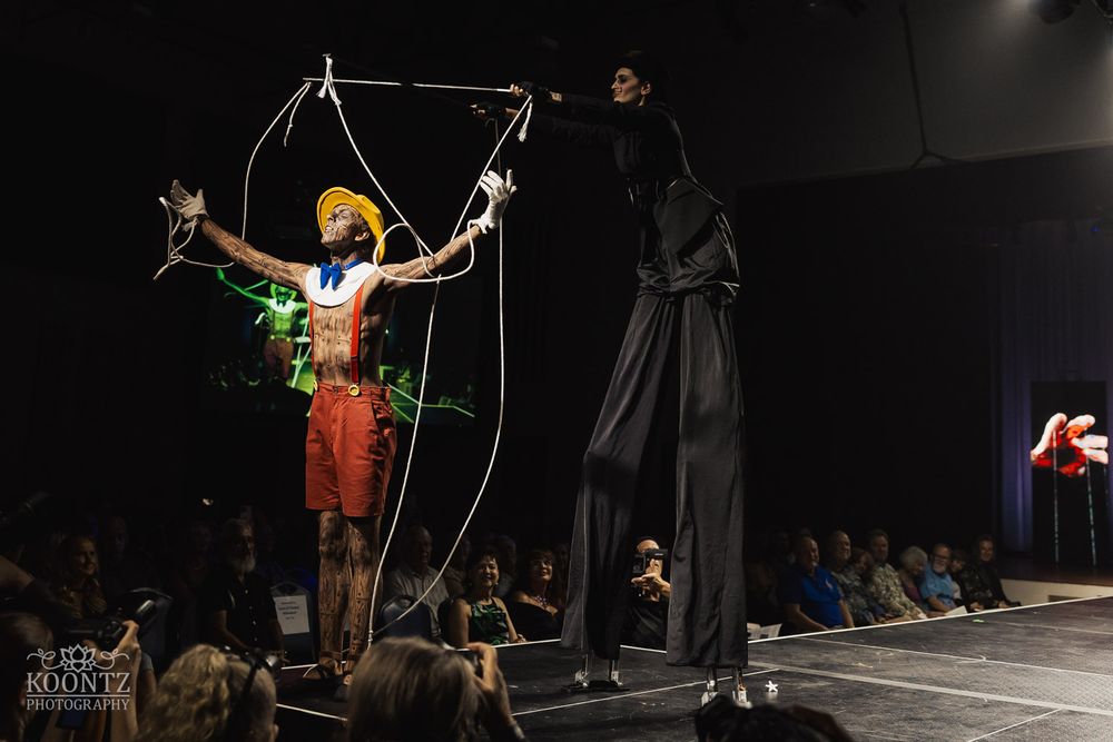 Performers on stage create dynamic poses with ropes and aerial equipment during a theatrical performance.