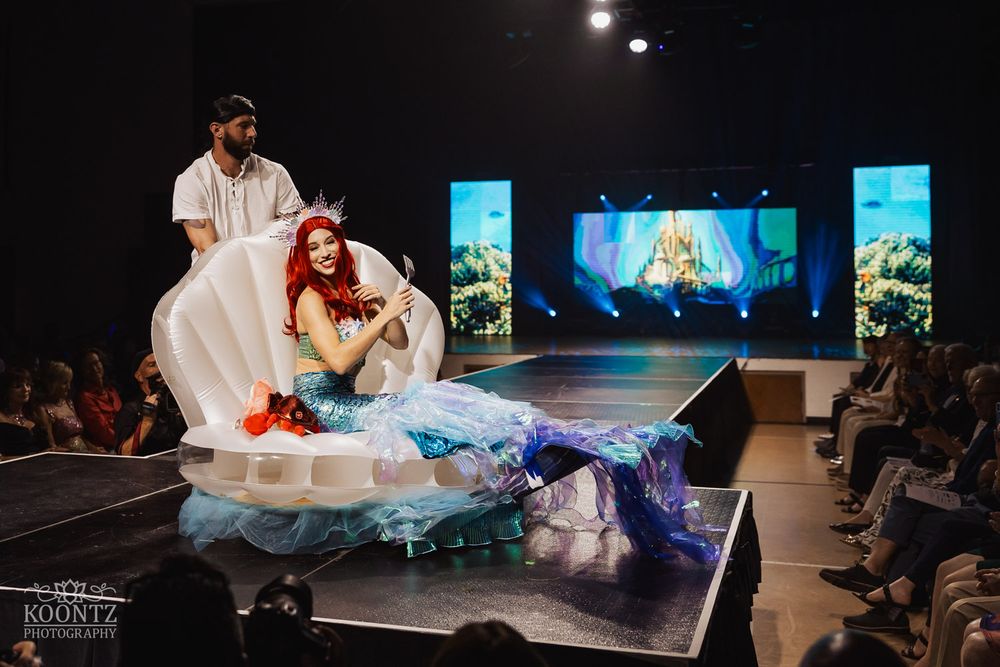 Dramatic stage performance featuring white flowing fabric against a dark backdrop.