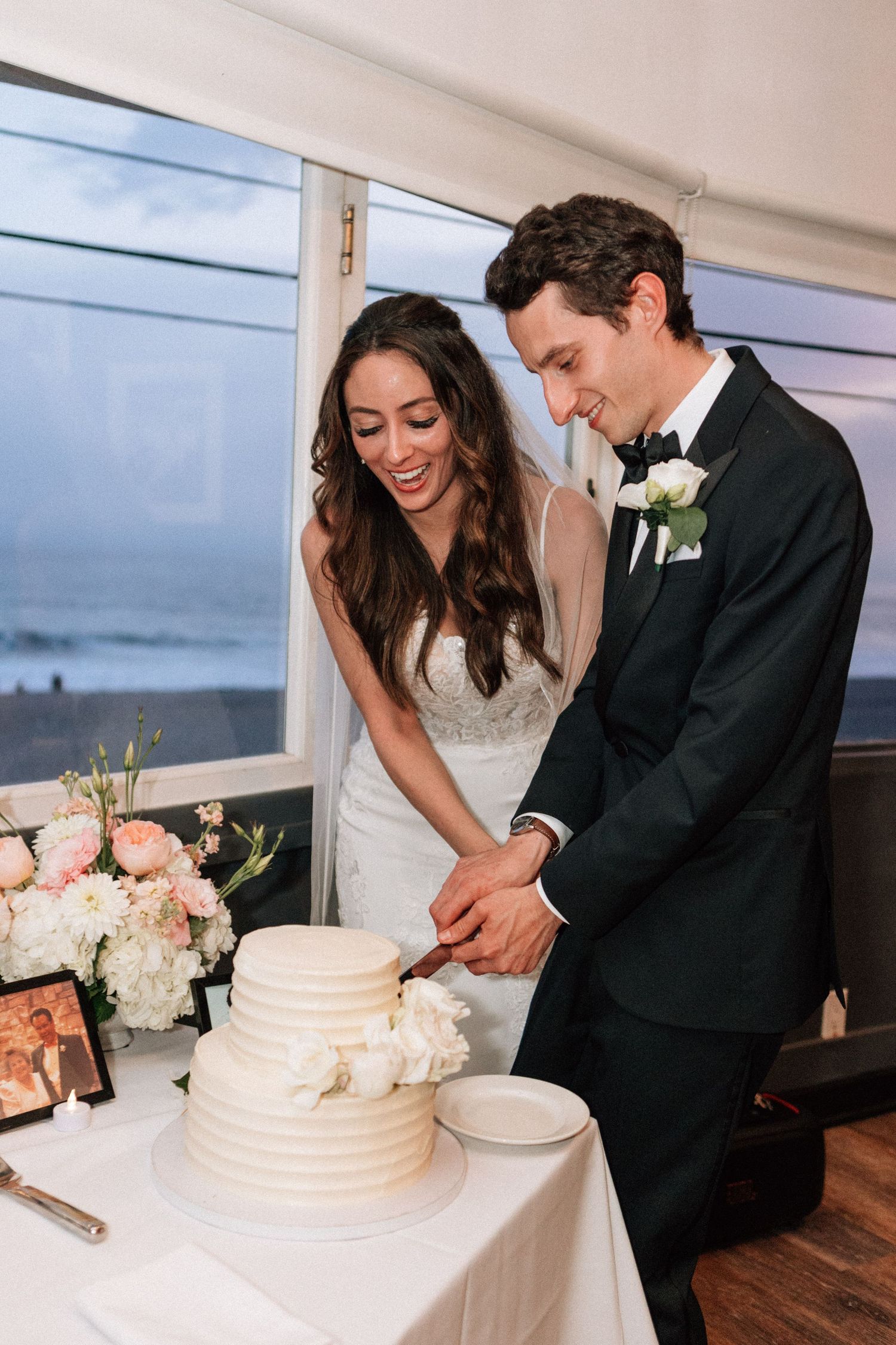 Joyful cake cutting moment at a small Malibu beach wedding dinner.