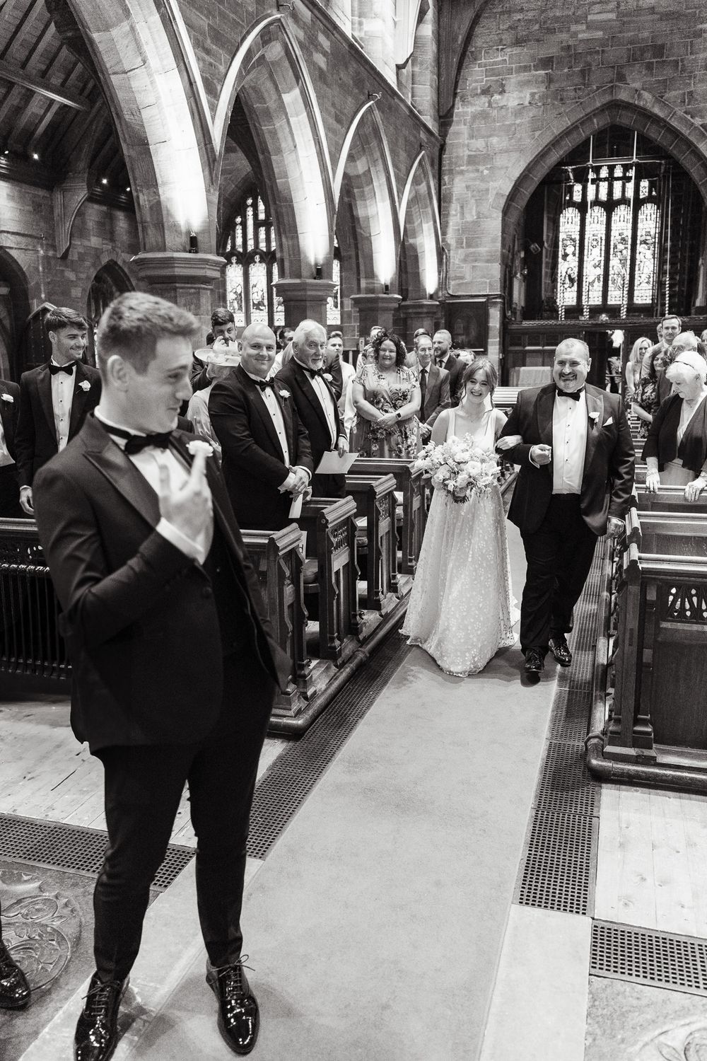 A joyous procession makes its way down the aisle of a historic stone church during a wedding ceremony.