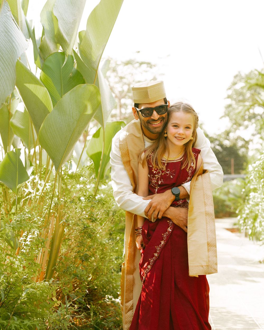 Outdoor portrait session in a garden with lush green plants and natural sunlight.