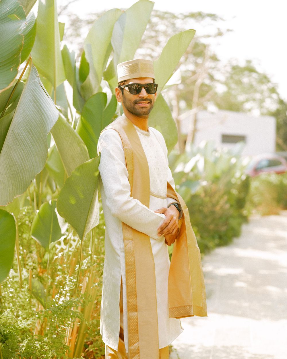Stylish outdoor photoshoot featuring white and gold attire among tropical foliage.